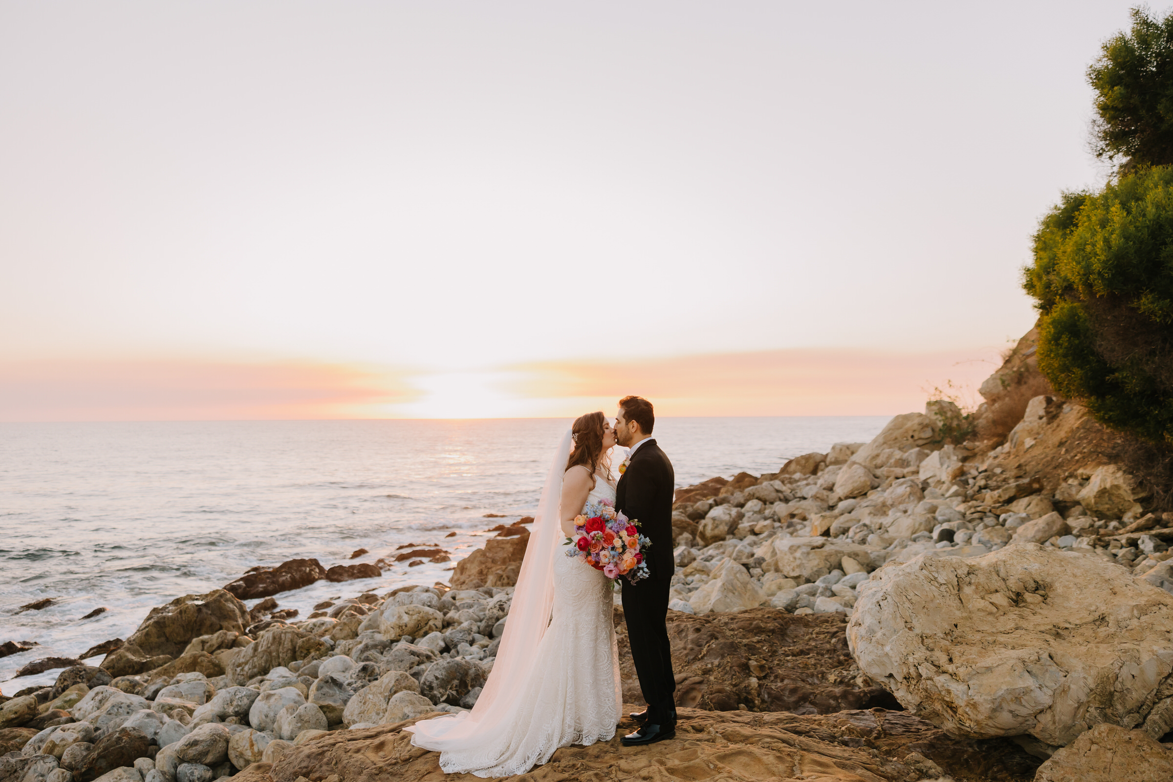 A high-fashion wedding portrait of Rebecca and Maz on the edge of the Palos Verdes cliffs at Terranea Resort during sunset.