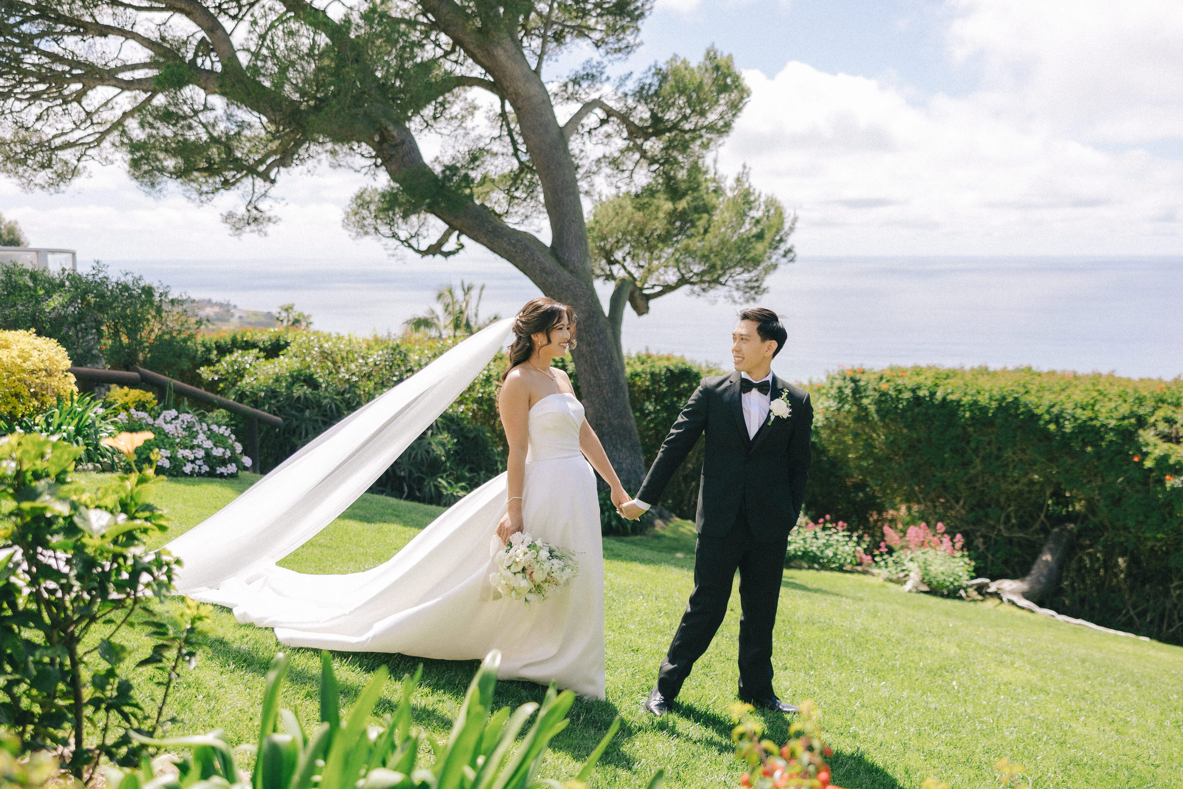 Yzie and Kevin standing on the balcony of La Venta Inn with the Pacific Ocean and the Los Angeles coastline in the background.