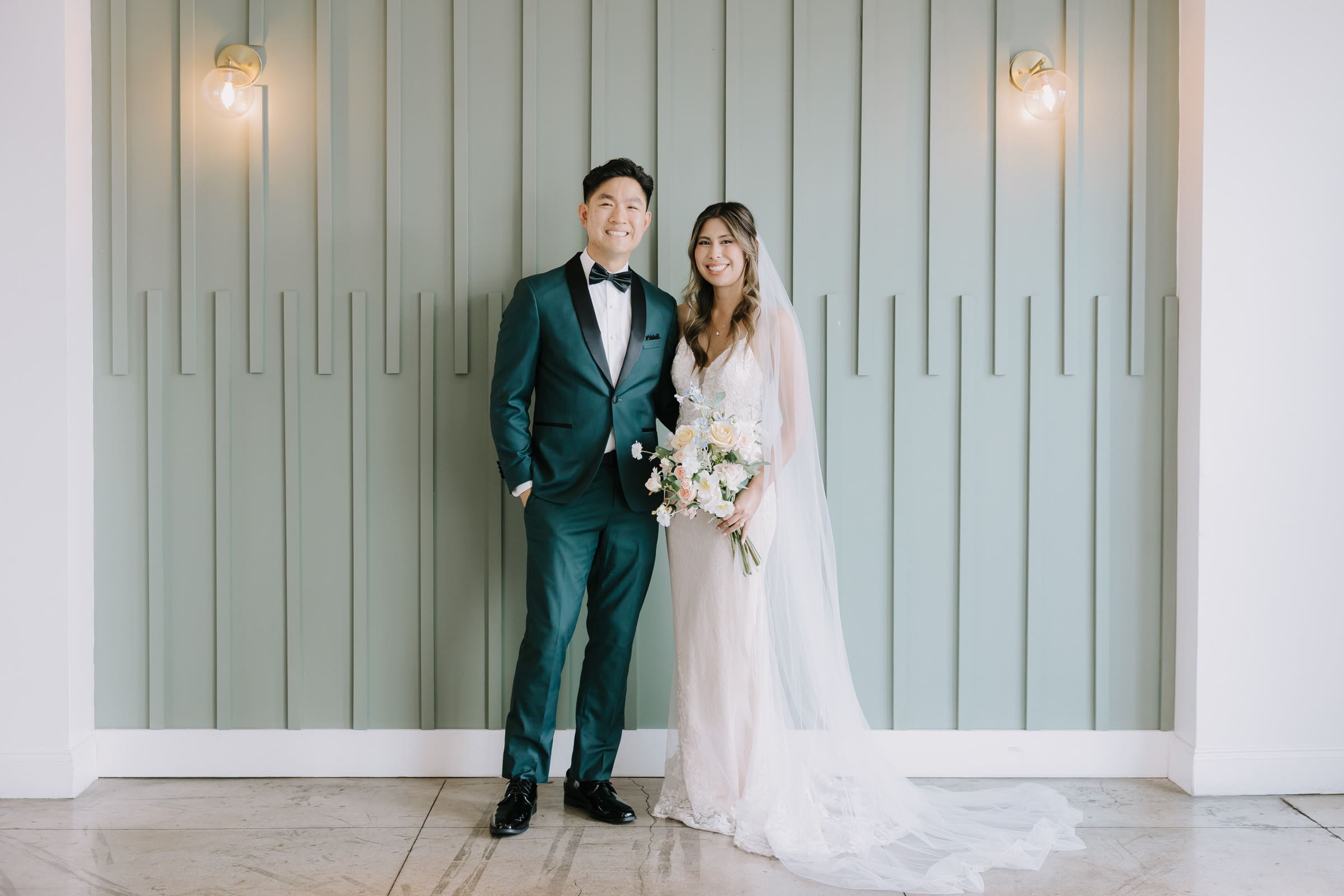 Ben and Sarina sharing a laugh against the whitewashed brick wall and original bow truss ceilings of The Colony House Anaheim.
