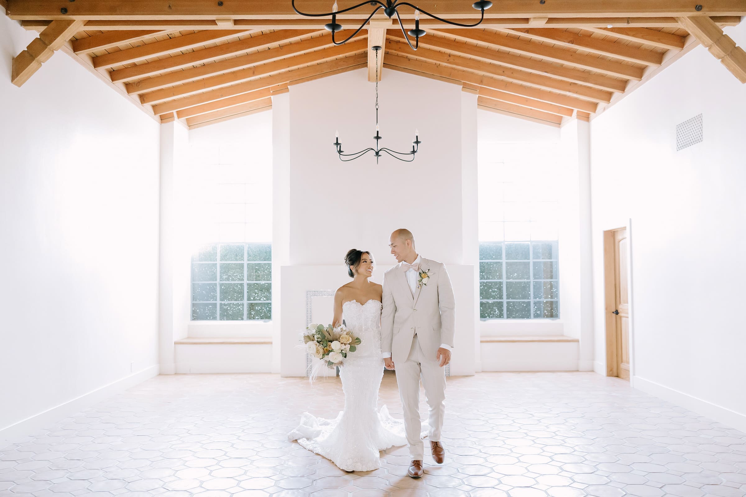 Kathrina and Jeff standing under the 100-year-old olive trees at Grand Gimeno with modern tropical floral installations.