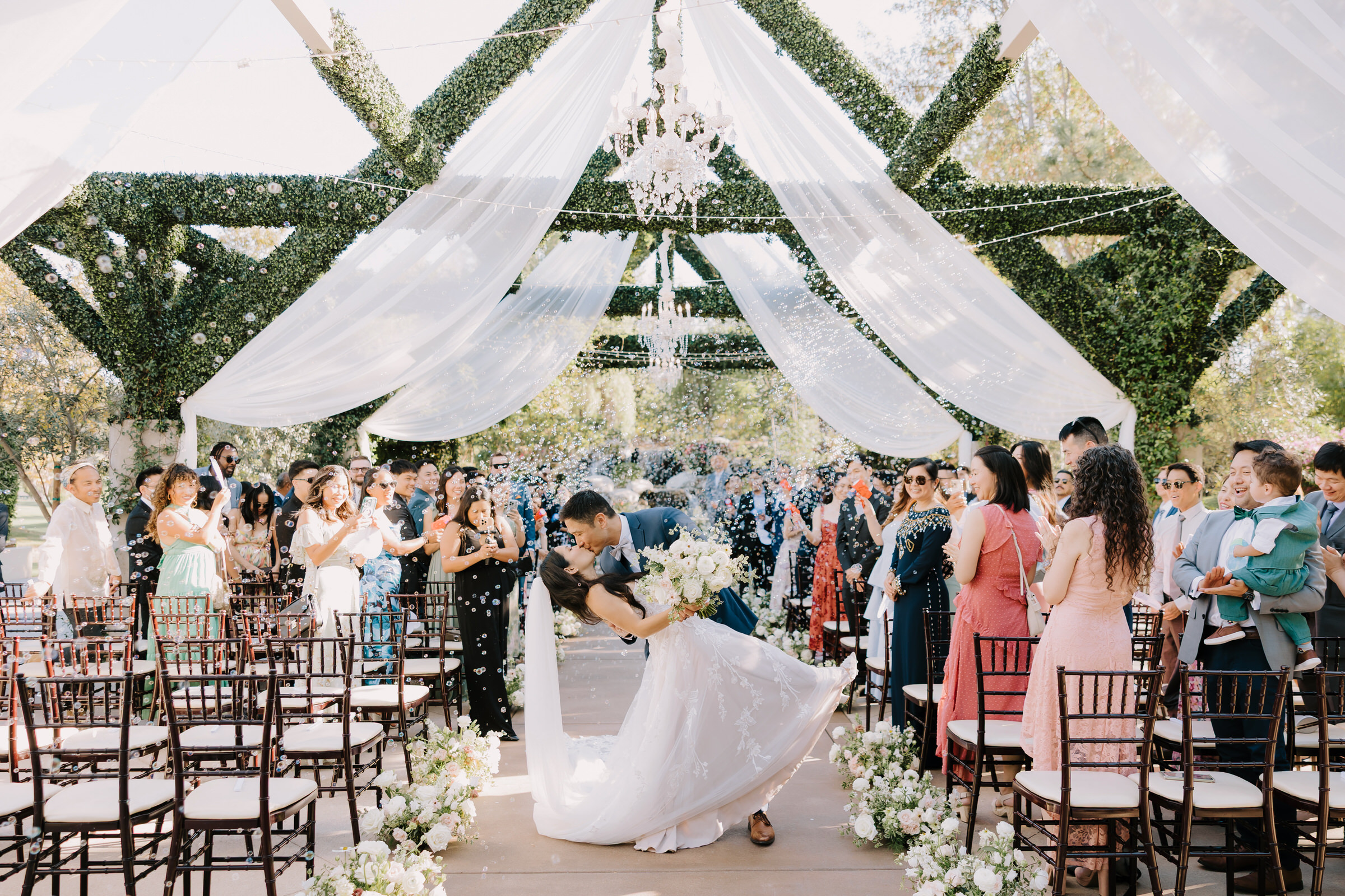 Valerie and Hank posing on the wooden bridge at Coyote Hills Golf Course with lush greenery and waterfalls in the background.