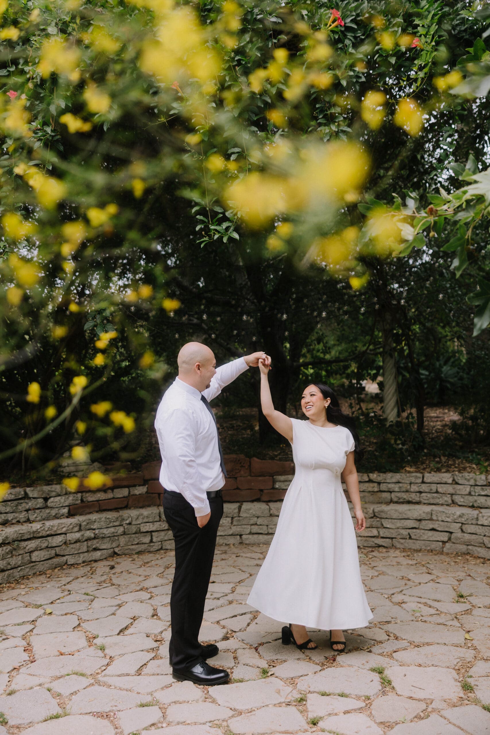 A couple embracing during their Pasadena City Hall engagement photos, showcasing the historic architecture and lush greenery of Arlington Garden.