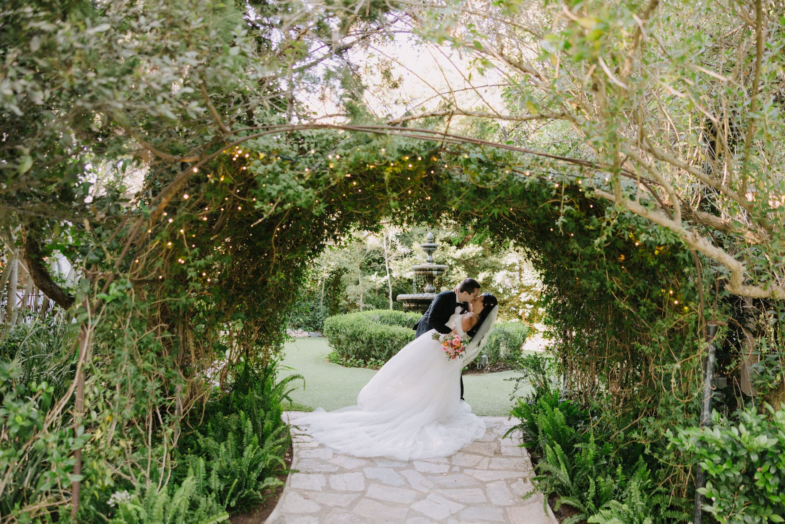Bride and groom posing in front of a colorful 1,001 Japanese paper crane backdrop at a Twin Oaks Garden Estate wedding in San Marcos.